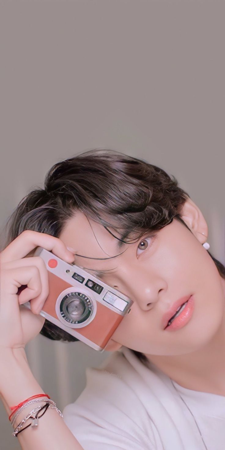 a young man holding an old camera up to his face and looking at the camera