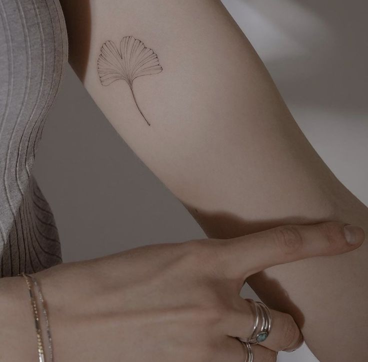 a woman's arm with a small flower tattoo on it