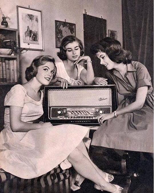 three women sitting on a couch with an old radio