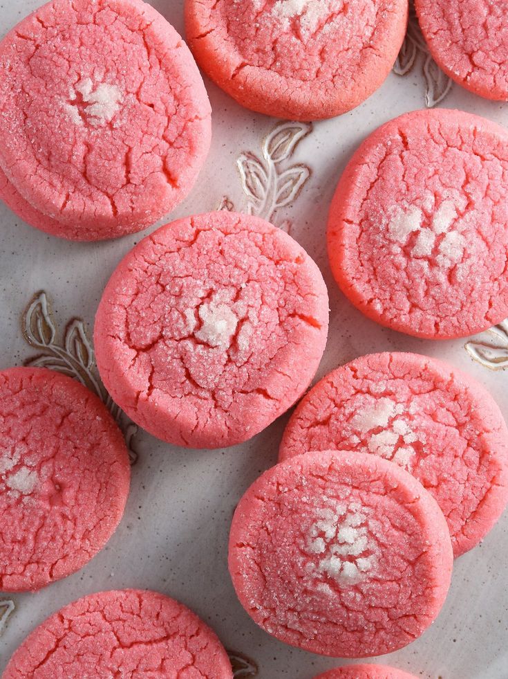 some pink cookies are on a white plate