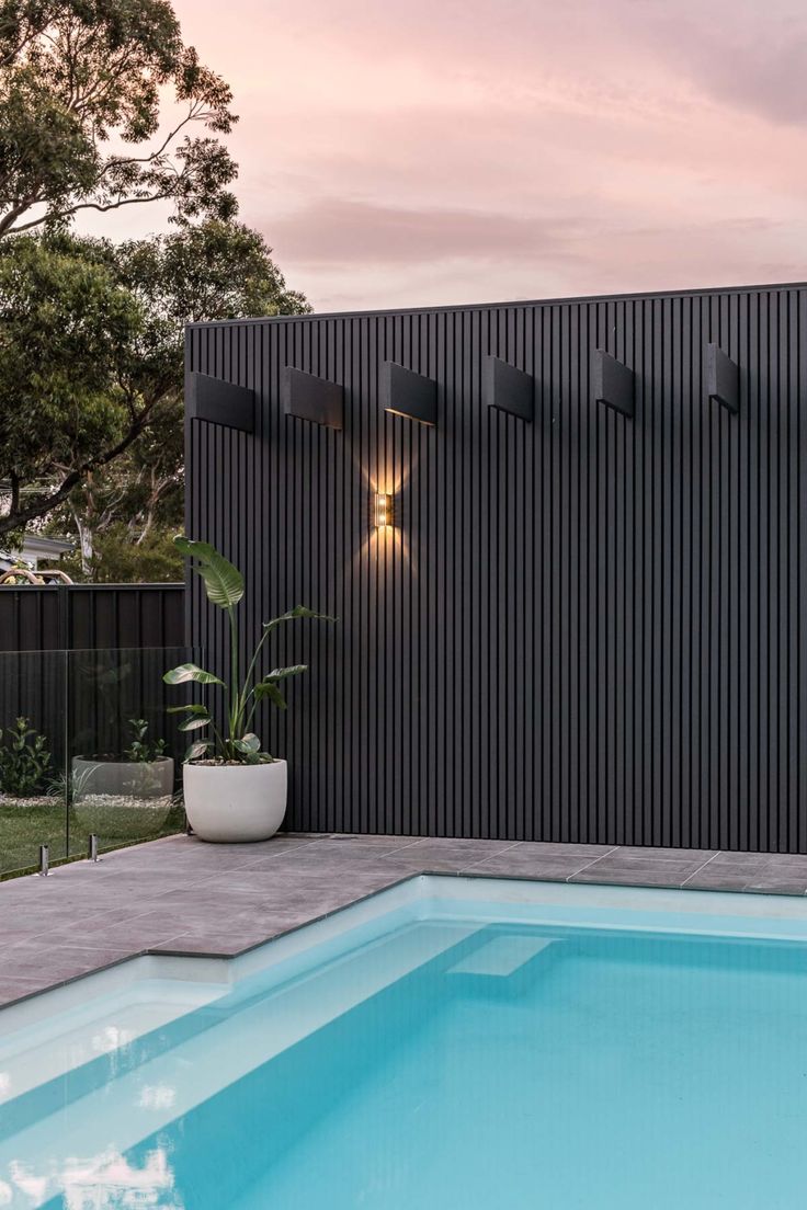 an outdoor pool with a fenced in area and potted plant next to it