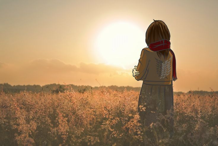 a woman standing in the middle of a field at sunset