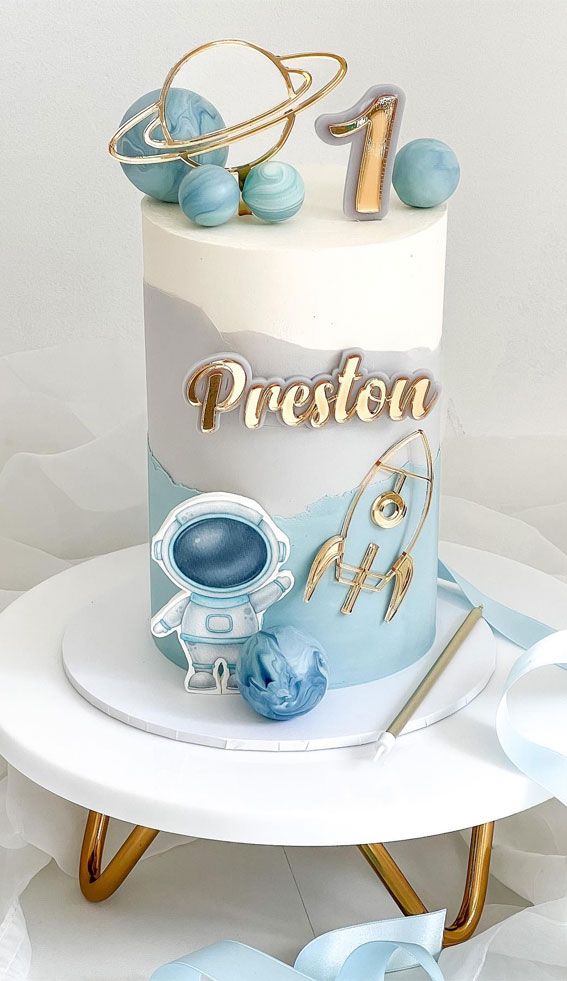 a blue and white birthday cake with gold lettering on the top is sitting on a table