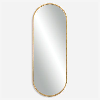 an oval gold framed mirror on a white wall, with the reflection of a person's face in it