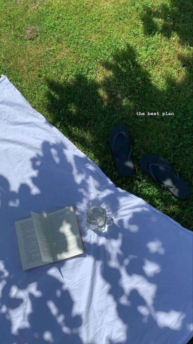 an open book sitting on top of a white cloth covered table next to a tree