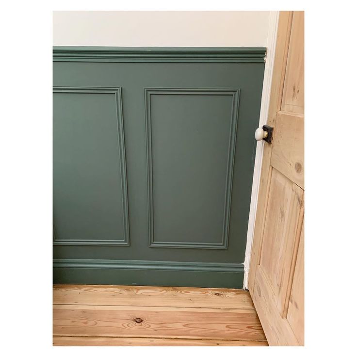 an open door in a room with wood floors and green painted paneling on the walls