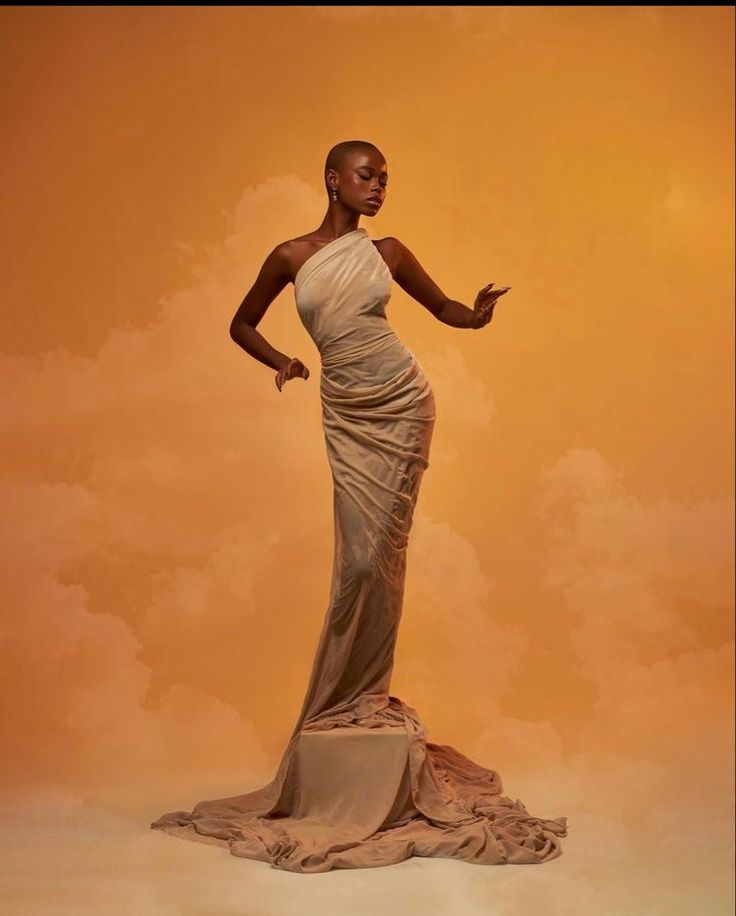 a woman standing on top of a rock in front of an orange sky with clouds