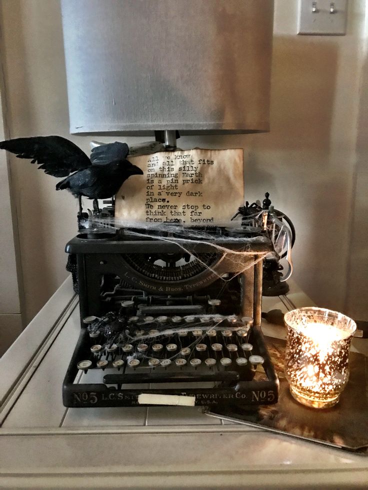 an old fashioned typewriter sitting on top of a table next to a glass candle