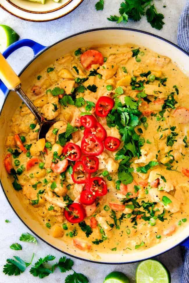 a large pan filled with food and garnished with cilantro, limes, and tomatoes