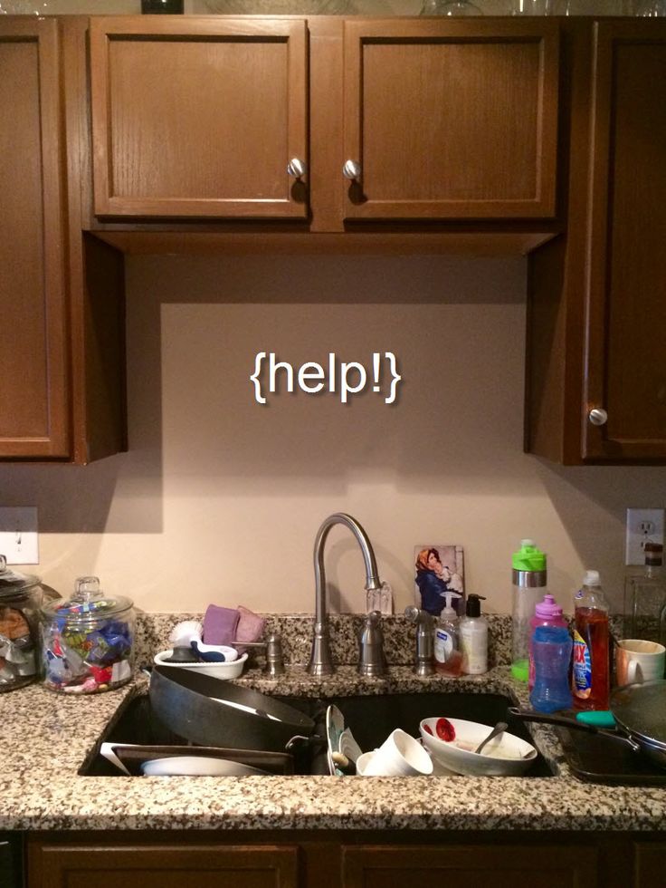 a kitchen sink filled with lots of clutter next to wooden cabinets and counter top