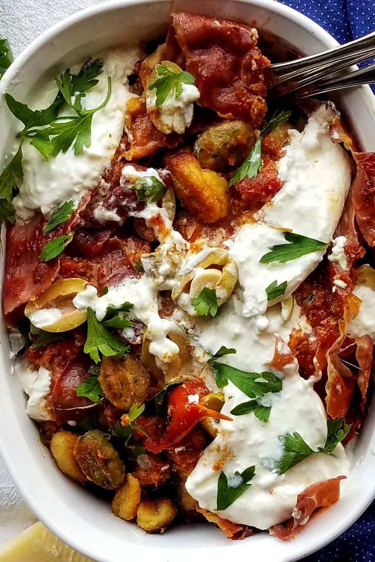 a white bowl filled with lots of food and garnished with parsley on top