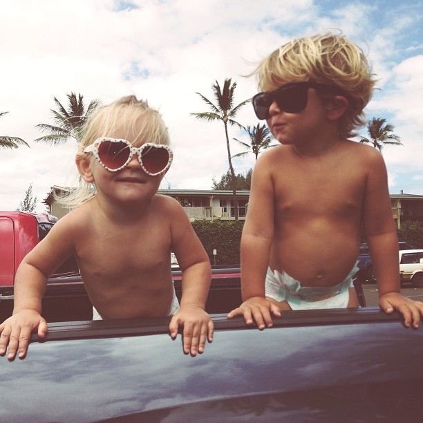 two children with sunglasses on their heads standing in the back of a car