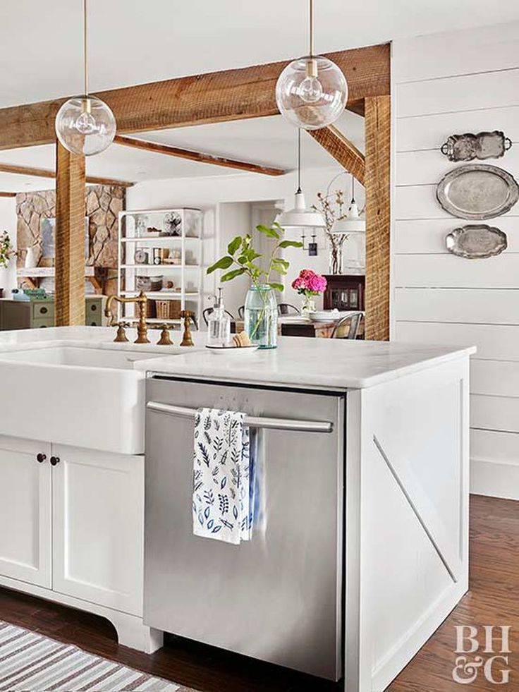 a kitchen with white cabinets and stainless steel dishwasher in front of the sink