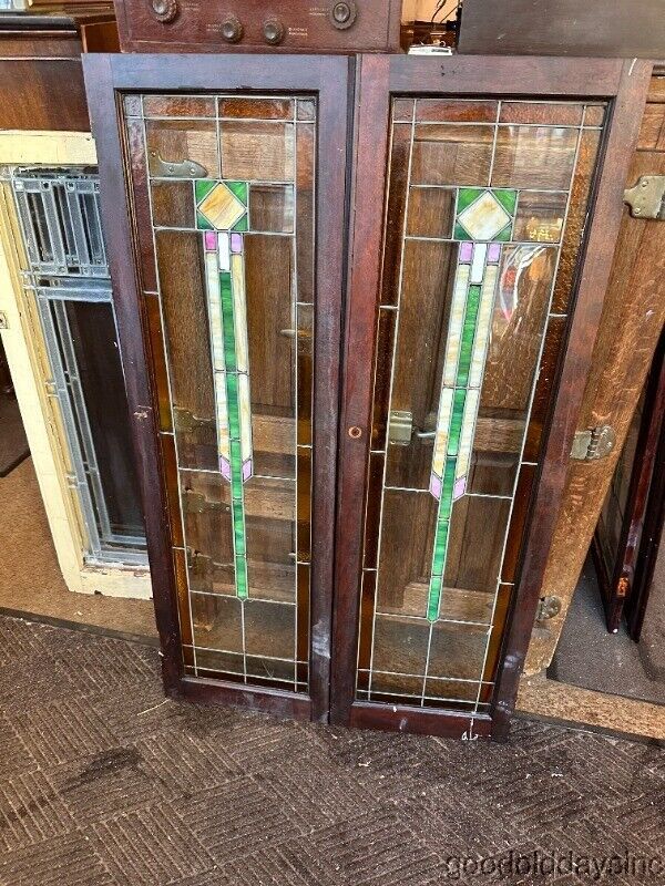 two stained glass doors sitting next to each other in front of a cabinet with drawers