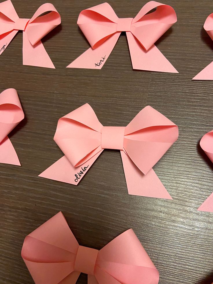 pink paper bows with name tags on them sitting on a table next to each other