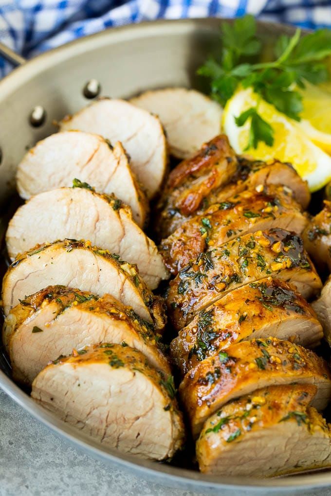 sliced pork with herbs and lemons in a pan