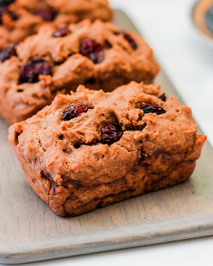 three chocolate chip muffins sitting on top of a cutting board