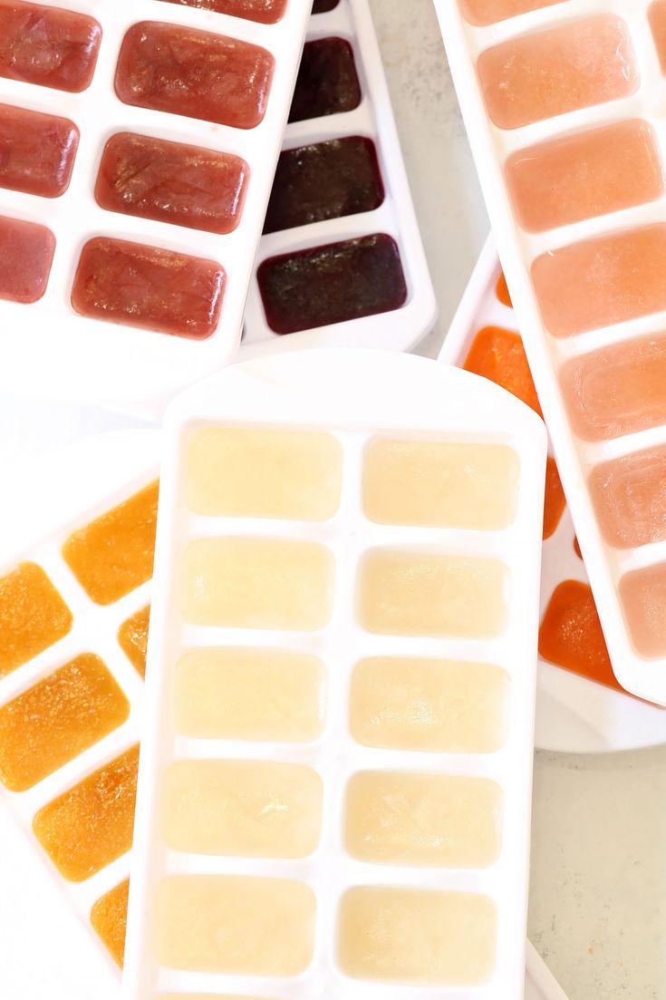 four ice trays filled with different types of fruit jelly and orange jello bars