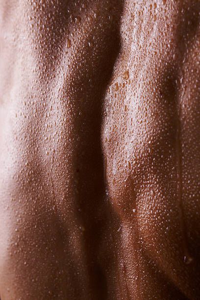 the back of a man's torso covered in brown paint and water drops on it