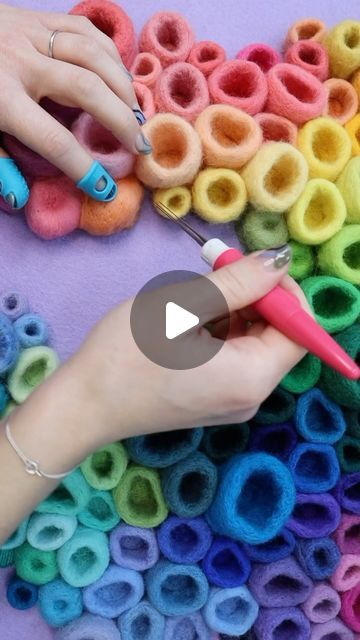 a woman is using scissors to make colorful felted rings with crochet hooks