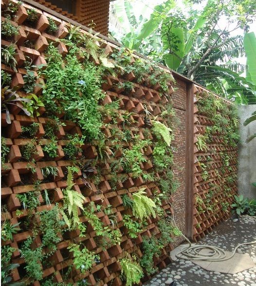 a fence made out of bricks with plants growing on it