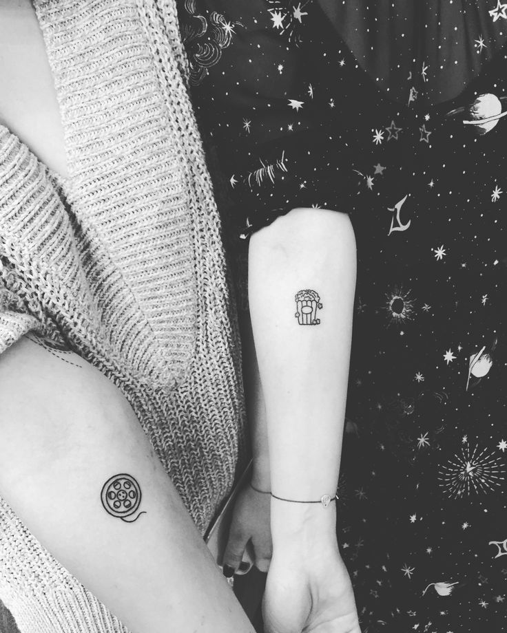 two people holding hands with tattoos on their arms and one has a small tattoo on the arm