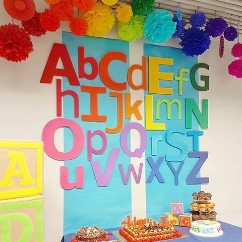 a table topped with lots of colorful paper pom poms next to a wall