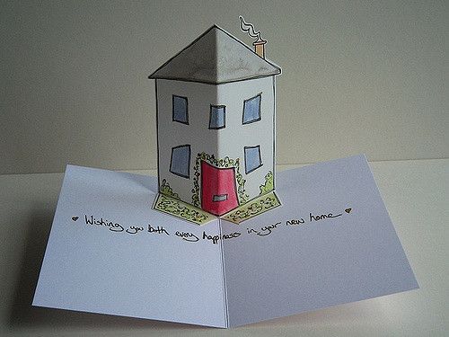 an origami house with a red door is on top of a piece of paper