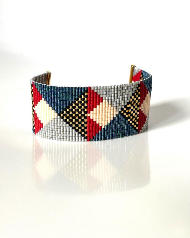 a close up of a bracelet on a white surface with a reflection in the background