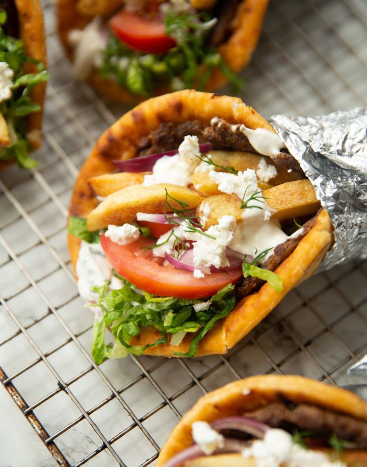 some tacos are sitting on a rack with tin foil and other food items in the background