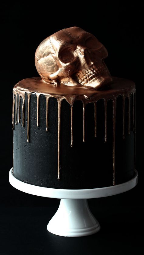 a black cake with gold icing and a skull on top