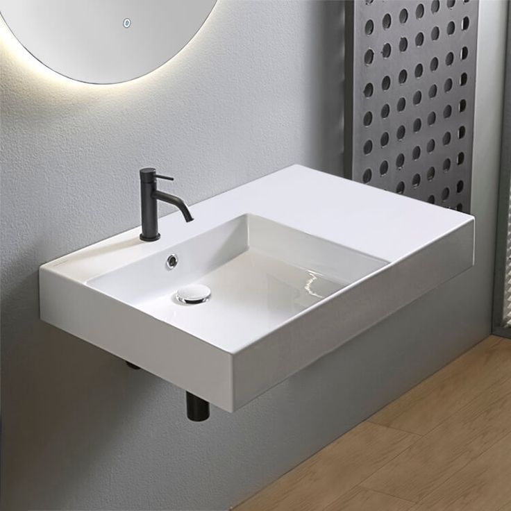 a white bathroom sink sitting next to a wall mounted faucet under a mirror