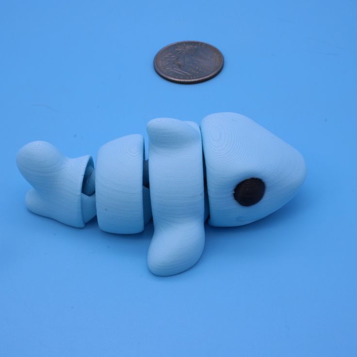 a penny sitting on top of a blue surface next to a toy fish with its mouth open