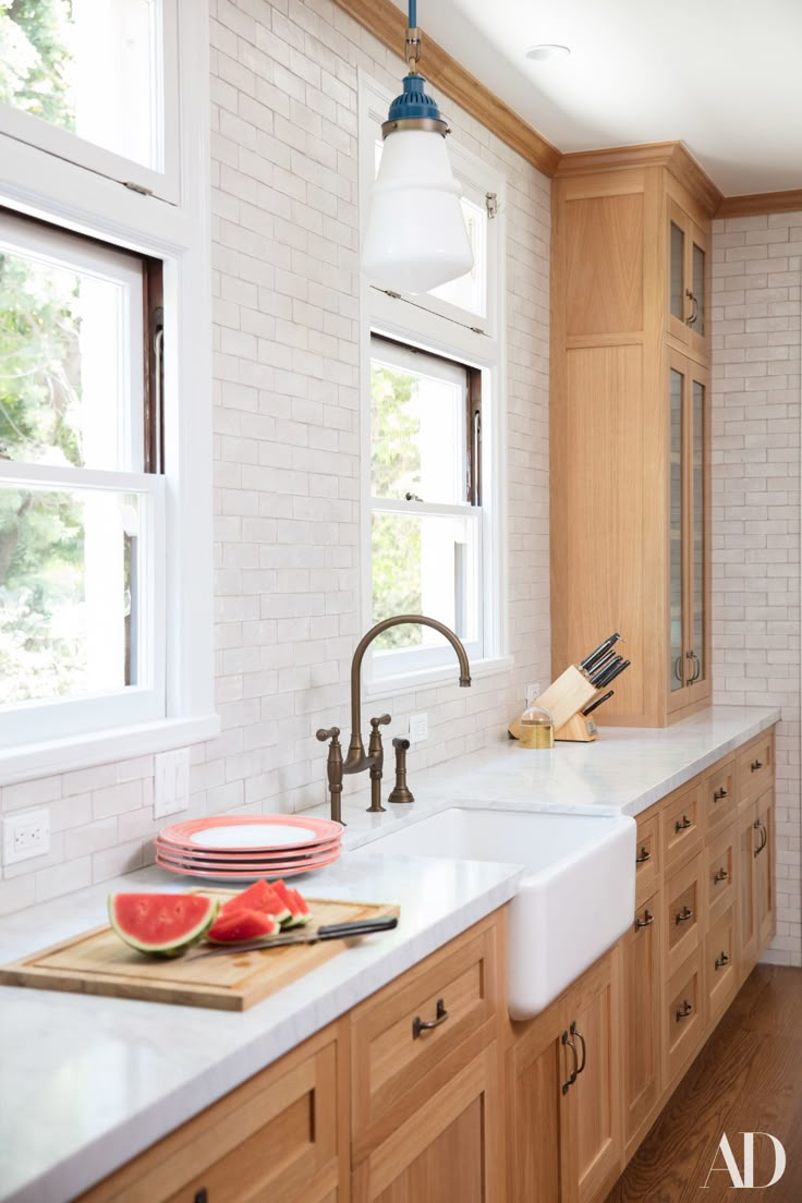 a kitchen with wooden cabinets and white counter tops, along with a large window over the sink