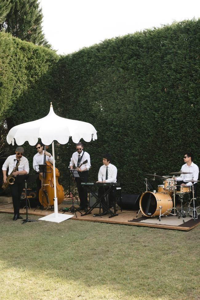 a group of men playing instruments under a white umbrella