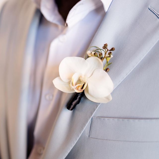 a man in a suit and tie with a flower on his lapel buttonhole