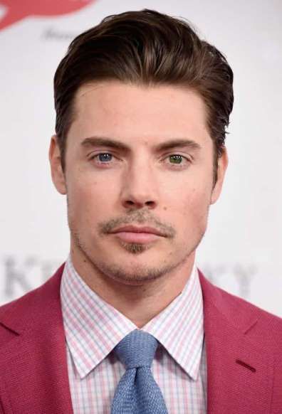 a close up of a person wearing a suit and tie with a moustache