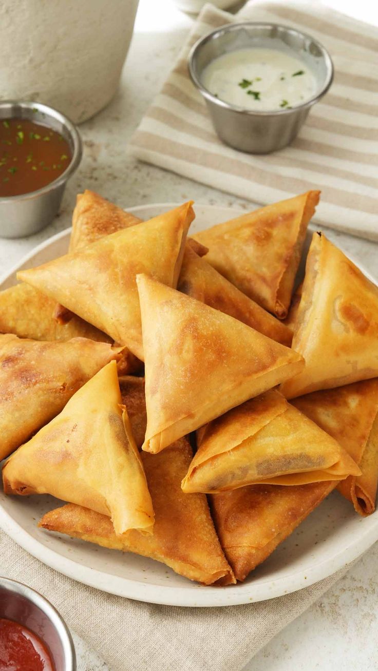 some food is on a white plate with sauces and dipping sauce in the background