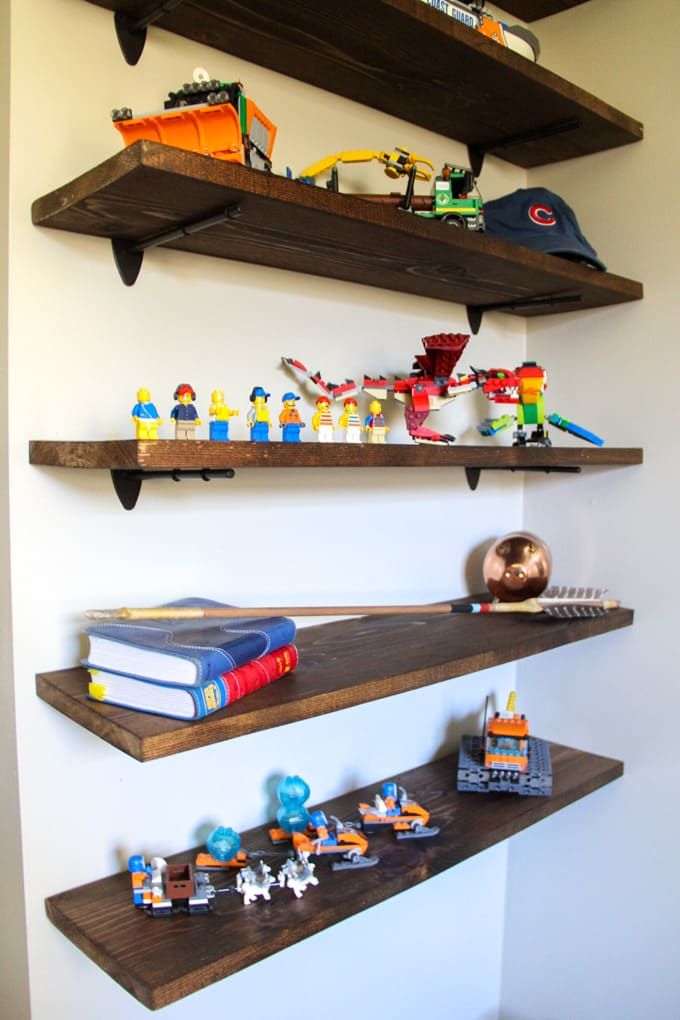 two wooden shelves with legos on them and bookshelves above each shelf in the corner