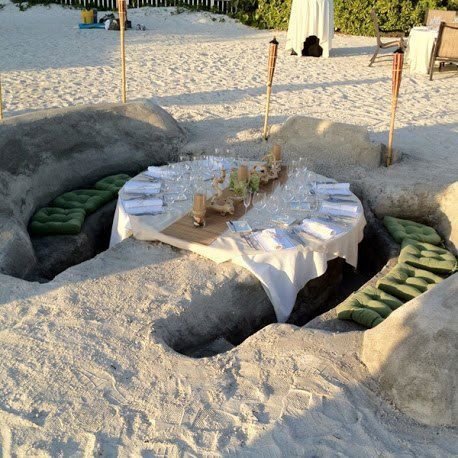 a table is set up in the sand for an outdoor dinner