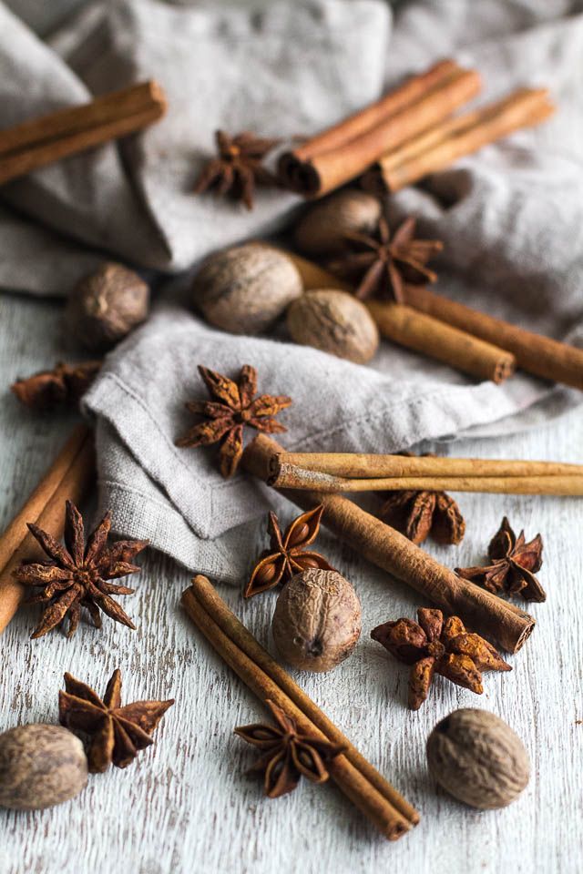 cinnamon and star anise on top of a white cloth with some cinnamon in the background