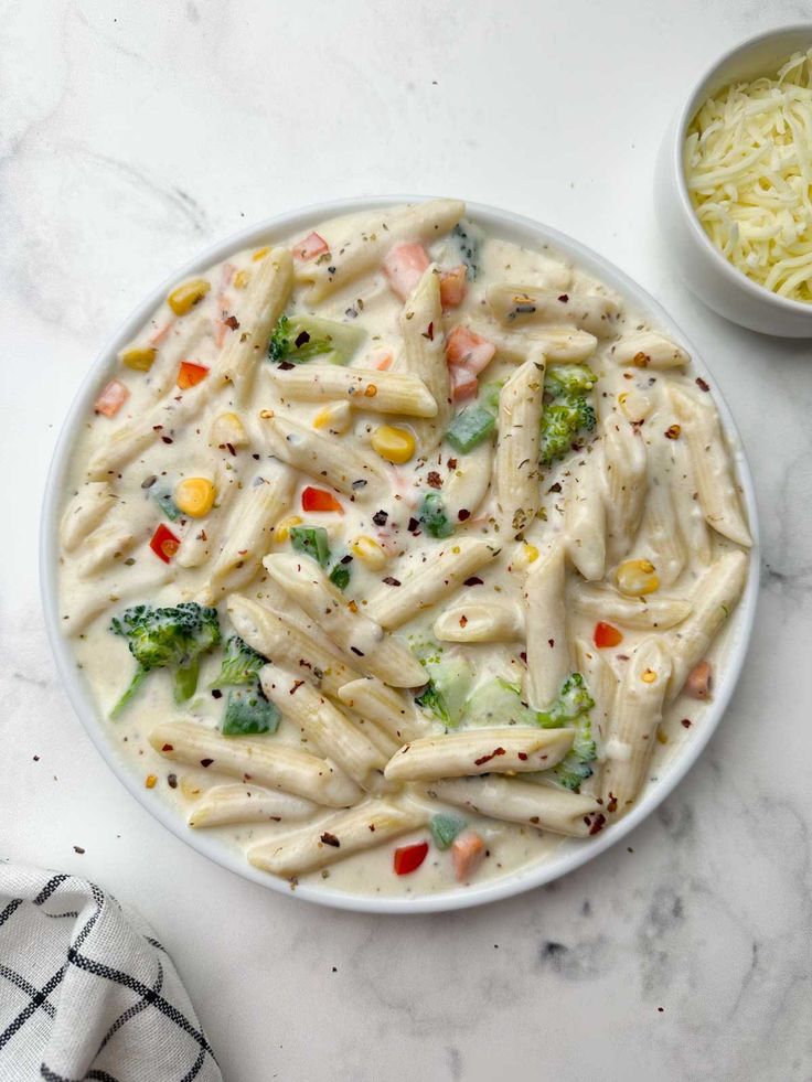 a bowl filled with pasta and broccoli on top of a white marble counter