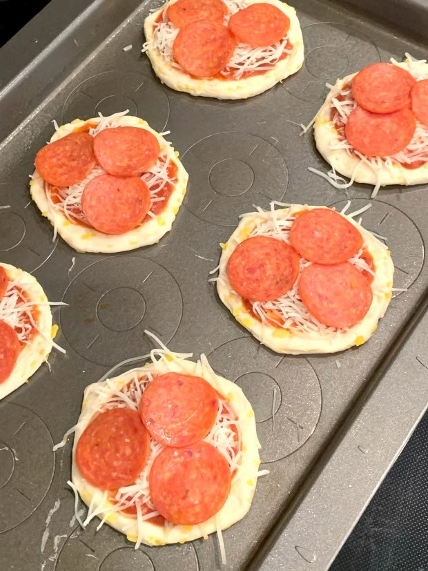 mini pizzas with cheese and pepperoni on top in a baking pan, ready to go into the oven