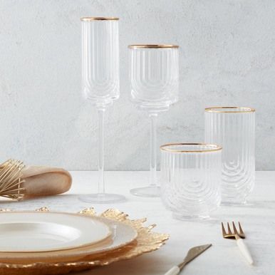 a table topped with plates and glasses filled with gold rimmed wine goblets