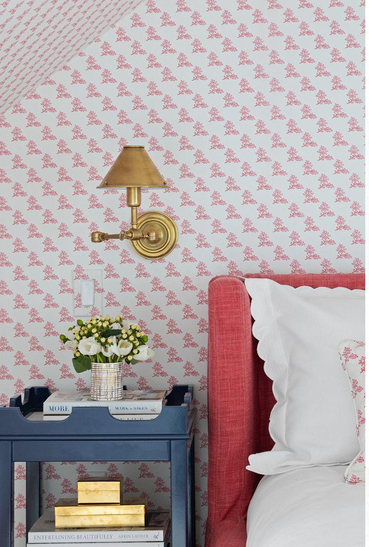 a bedroom with pink and white wallpaper, gold accents and a blue end table