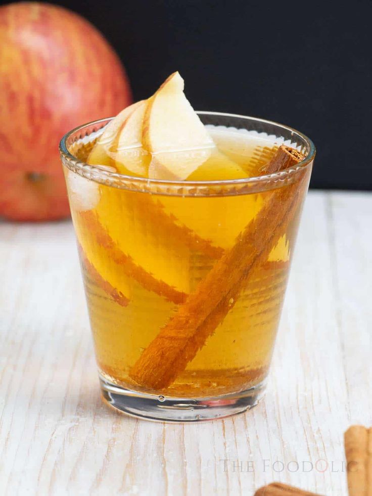 an apple cider in a glass with cinnamon stick garnish on the side