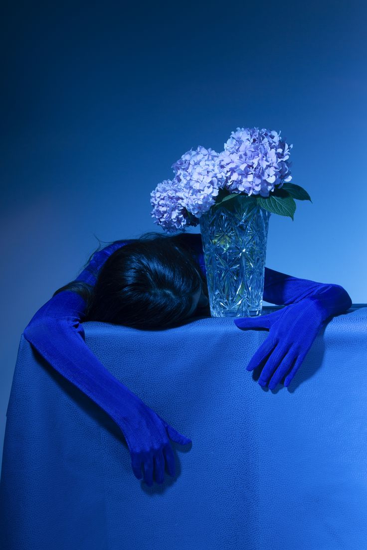 a woman with her head on the back of a table covered in blue cloths