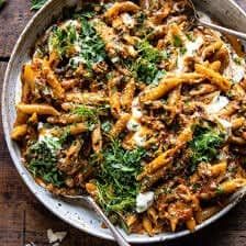 a bowl filled with pasta covered in sauce and parmesan cheese on top of a wooden table