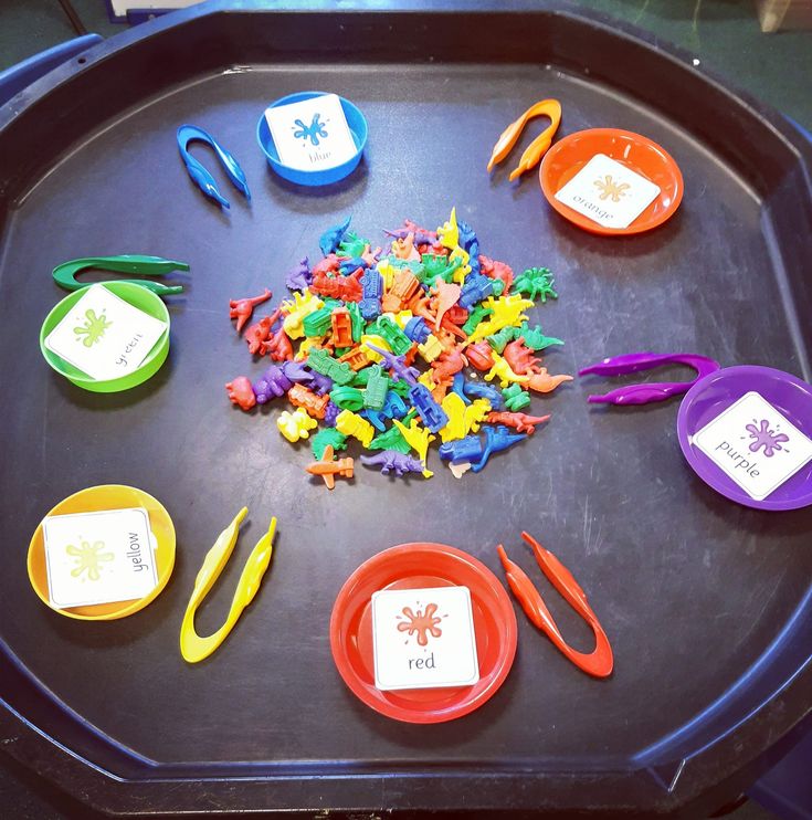 the tray is full of plastic toys and scissors for children to play with in it