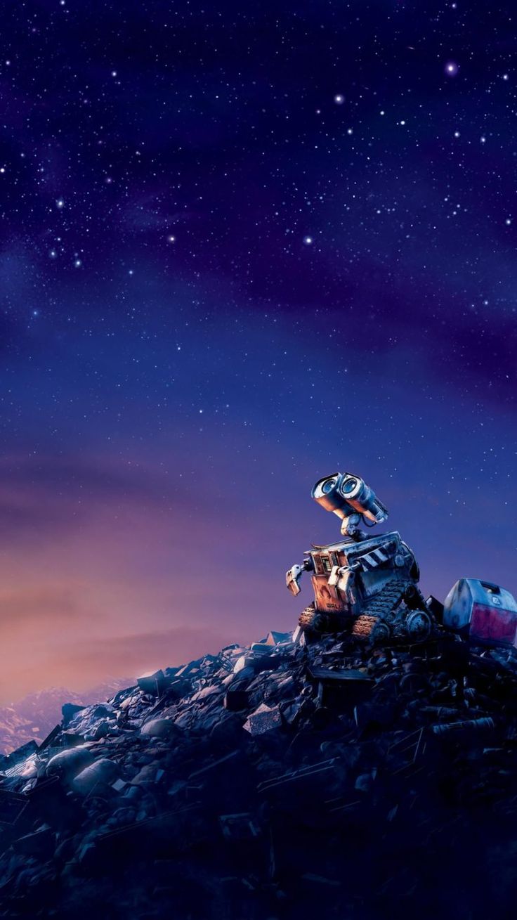 a man sitting on top of a pile of rocks under a sky filled with stars